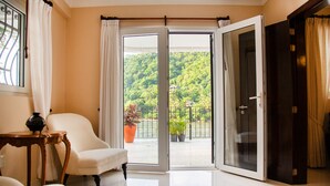 A room with a sliding glass door leading to a balcony with a view of a green landscape.
