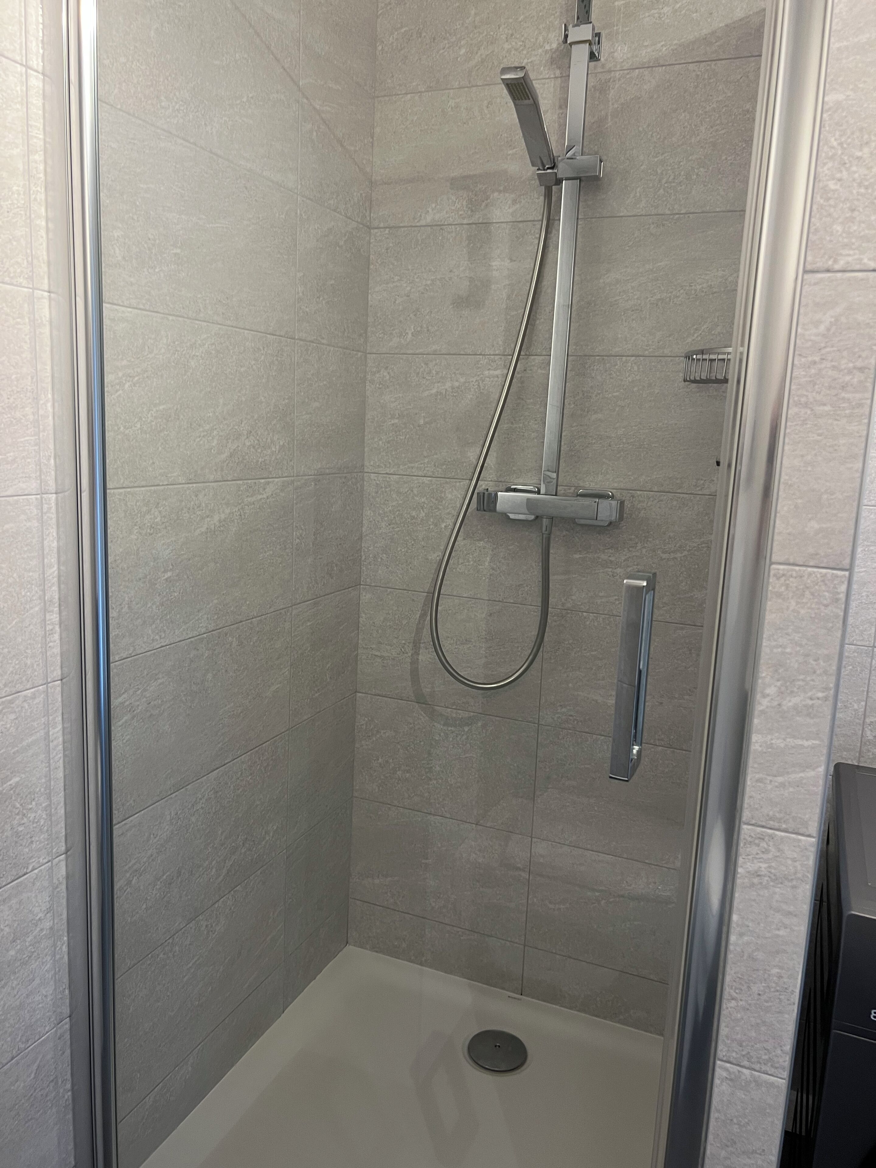 Eine Dusche mit Handbrause und Wandarmatur.