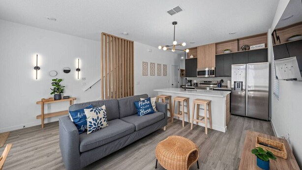 A modern kitchen with a central island, built-in appliances, and a wooden accent wall. - Gated Community  - Near Disney (Kissimmee)