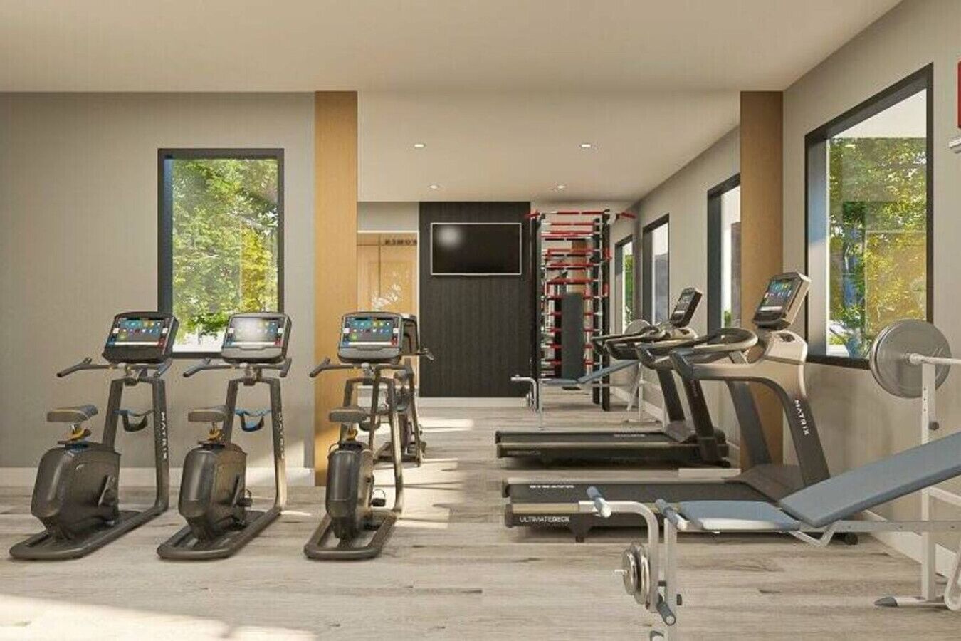Une salle de sport moderne équipée de tapis de course, de vélos elliptiques et d’un banc de musculation.
