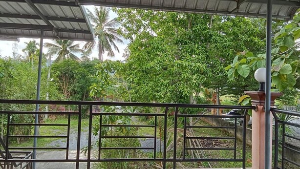 A covered outdoor area with a metal railing, a table, and chairs. - Hidden Gems  (Thung Song)