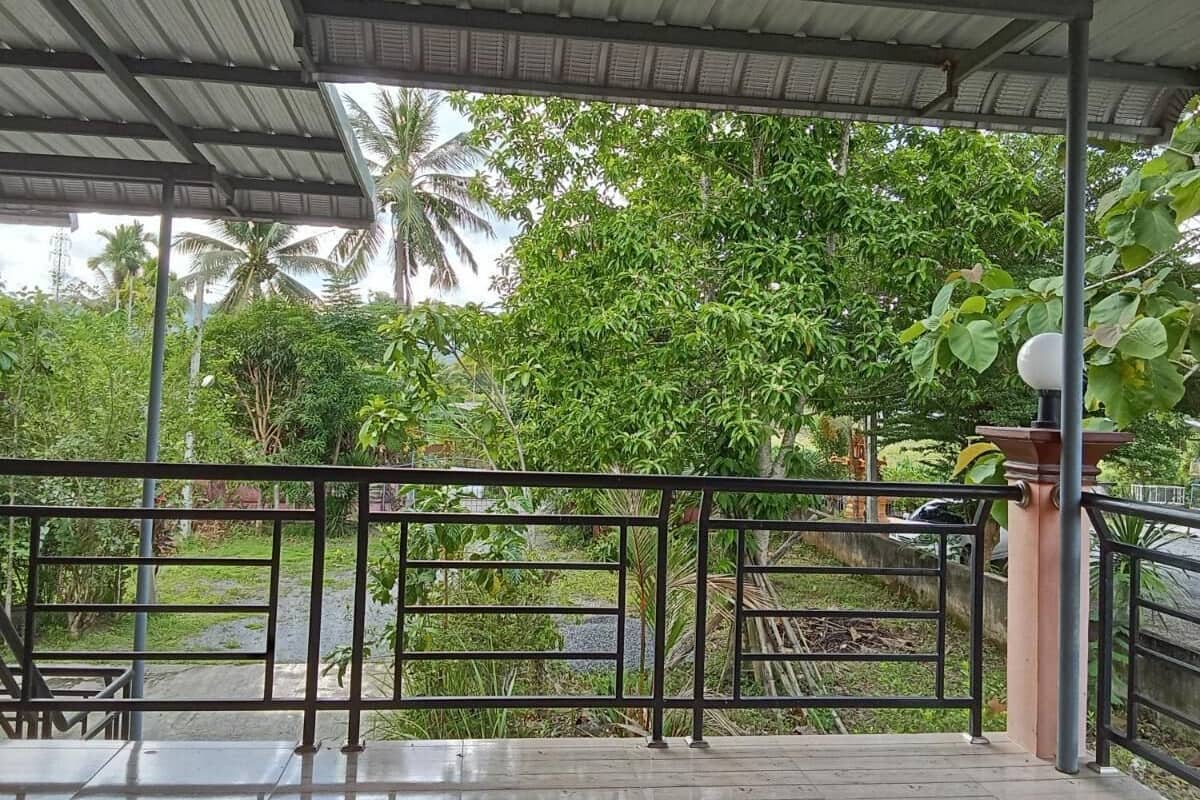 A covered outdoor area with a metal railing, a table, and chairs.