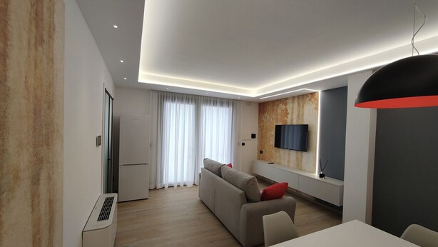 Una sala de estar moderna con un sofá, una mesa de comedor y un televisor montado en la pared.