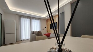 Una sala de estar moderna con una mesa blanca, un sofá y un televisor montado en la pared.
