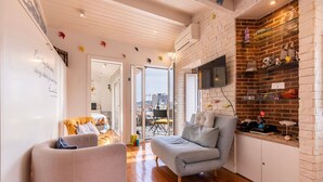 Een moderne woonkamer met een grijze bank, een gele fauteuil en een houten vloer.