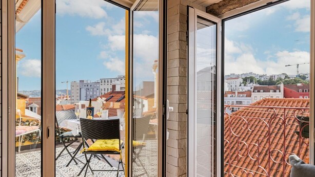 Een balkon met een tafel, stoelen, een fles en een glas.