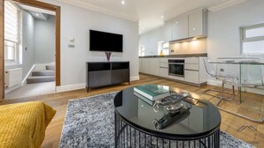 Un salon moderne avec un téléviseur à écran plat, une table basse en verre et un canapé.