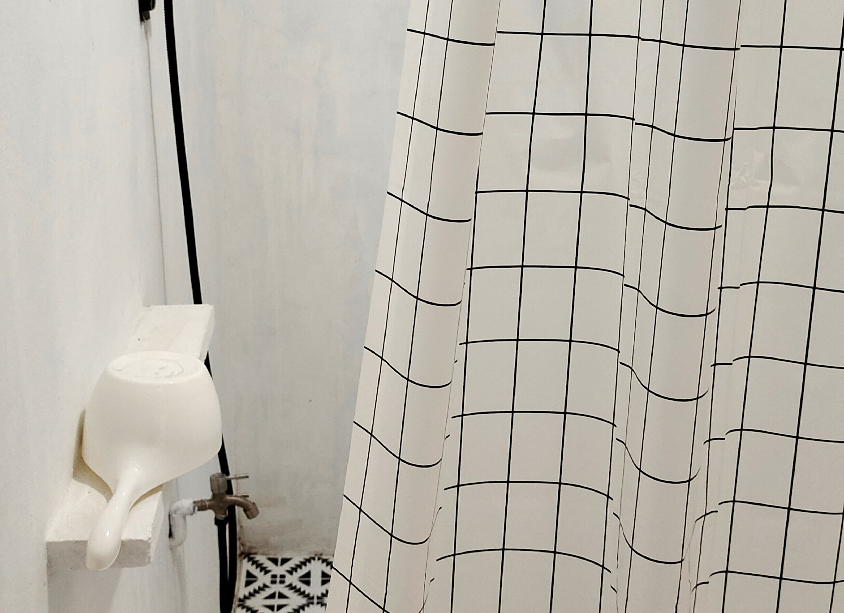 A bathroom with a shower curtain, a white toilet, and a handheld showerhead.
