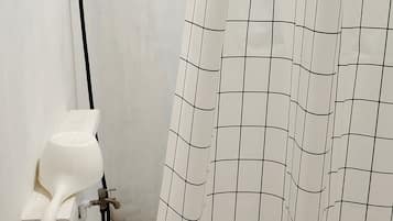 A bathroom with a shower curtain, a white toilet, and a handheld showerhead.