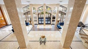 Un'ampia hall con una scalinata centrale, una reception e zone salotto.