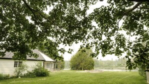 Ett hus med en gräsmatta och ett stort träd i förgrunden.