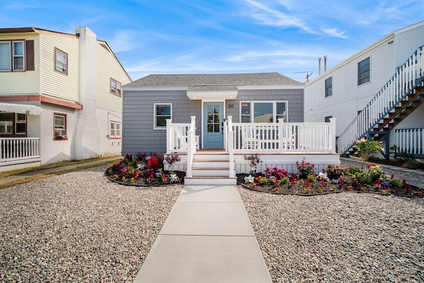 A residential building with a front porch, a gravel driveway, and flower beds. - Beach Bungalow -- 1.5 Blocks to Beach! (Brigantine)