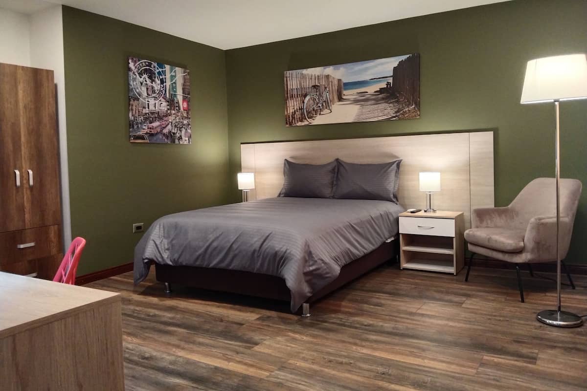 Een slaapkamer met een bed, nachtkastjes, een stoel en kunst aan de muren.