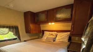 Une chambre avec un grand lit, des armoires en bois et une fenêtre donnant sur un beau paysage.