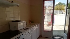 A kitchen with white cabinets, a microwave, a sink, and a window with a view of the outside. - Maison à la Campagne (Corneilhan)