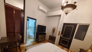 Una habitación de hotel con cama, escritorio, silla, televisor y puerta.