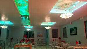 Un comedor con varias mesas y sillas, candelabros y obras de arte en las paredes.