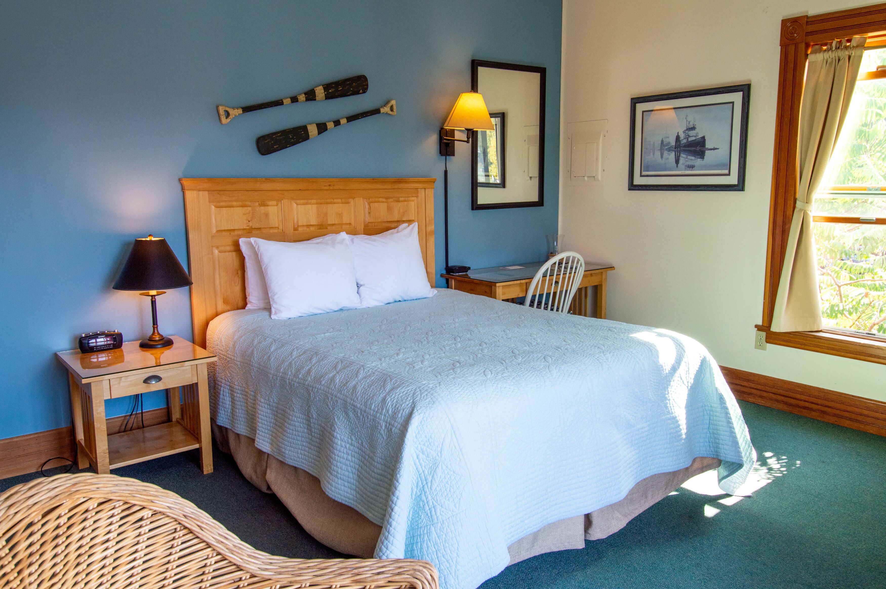 A neatly made bed with a wooden headboard, a bedside lamp, and a chair.