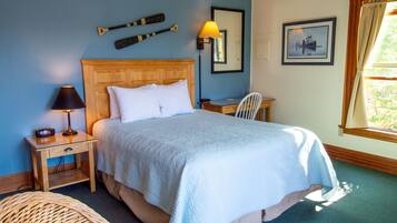 A neatly made bed with a wooden headboard, a bedside lamp, and a chair.