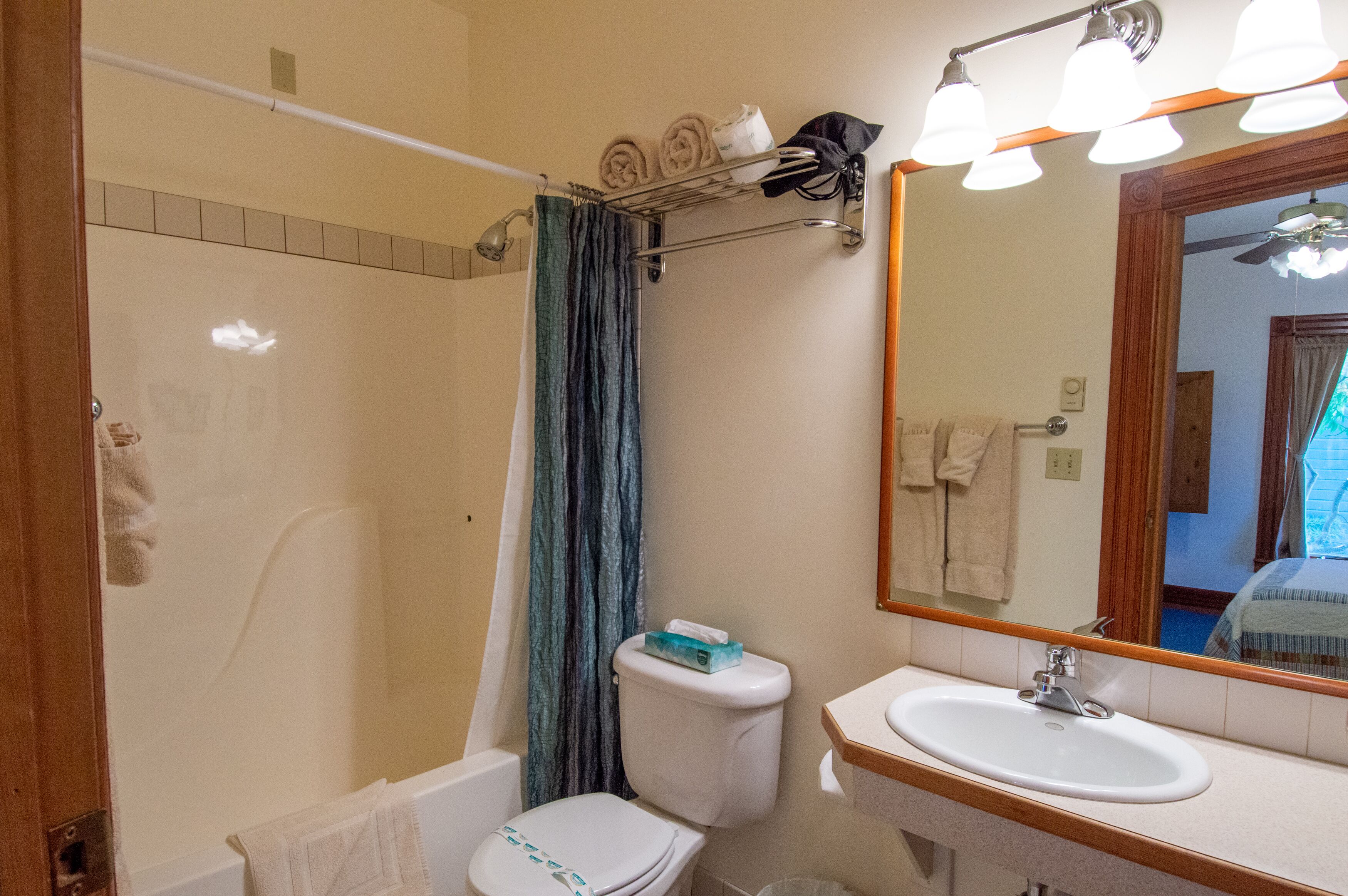 Et badeværelse med brusebad, toilet, håndvask og et spejl.