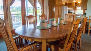 Una mesa de comedor de madera con sillas, rodeada de armarios de madera y una zona de cocina.
