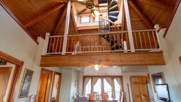Amplio loft con techos altos, una escalera en espiral y un comedor con muebles de madera.