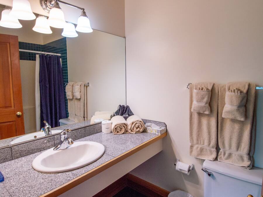 A bathroom with a sink, mirror, towel rack, and toilet.