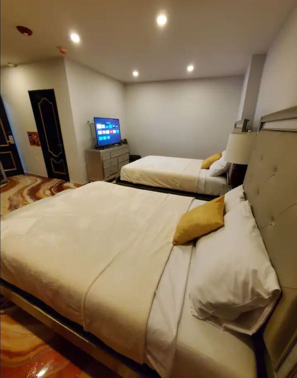 Habitación de hotel con dos camas, una televisión y un escritorio.
