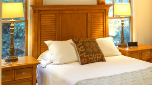 Una camera da letto con un letto grande, una testiera in legno, due comodini con lampade e un quadro sopra il letto.