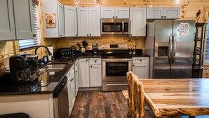 Une cuisine moderne avec des meubles blancs, des appareils en acier inoxydable et une table à manger en bois.