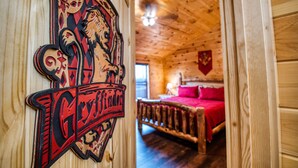 Un intérieur en bois avec un lit, une couverture rouge et un emblème fixé au mur.