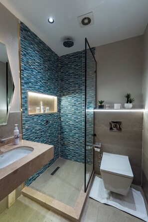Une salle de bain moderne avec une douche à parois de verre, un meuble-lavabo avec un miroir et des toilettes.