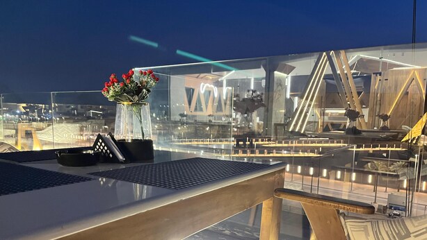 A modern dining area with a glass table, a vase with flowers, and a view of the cityscape. - Royal Great Pyramid INN (Giza)