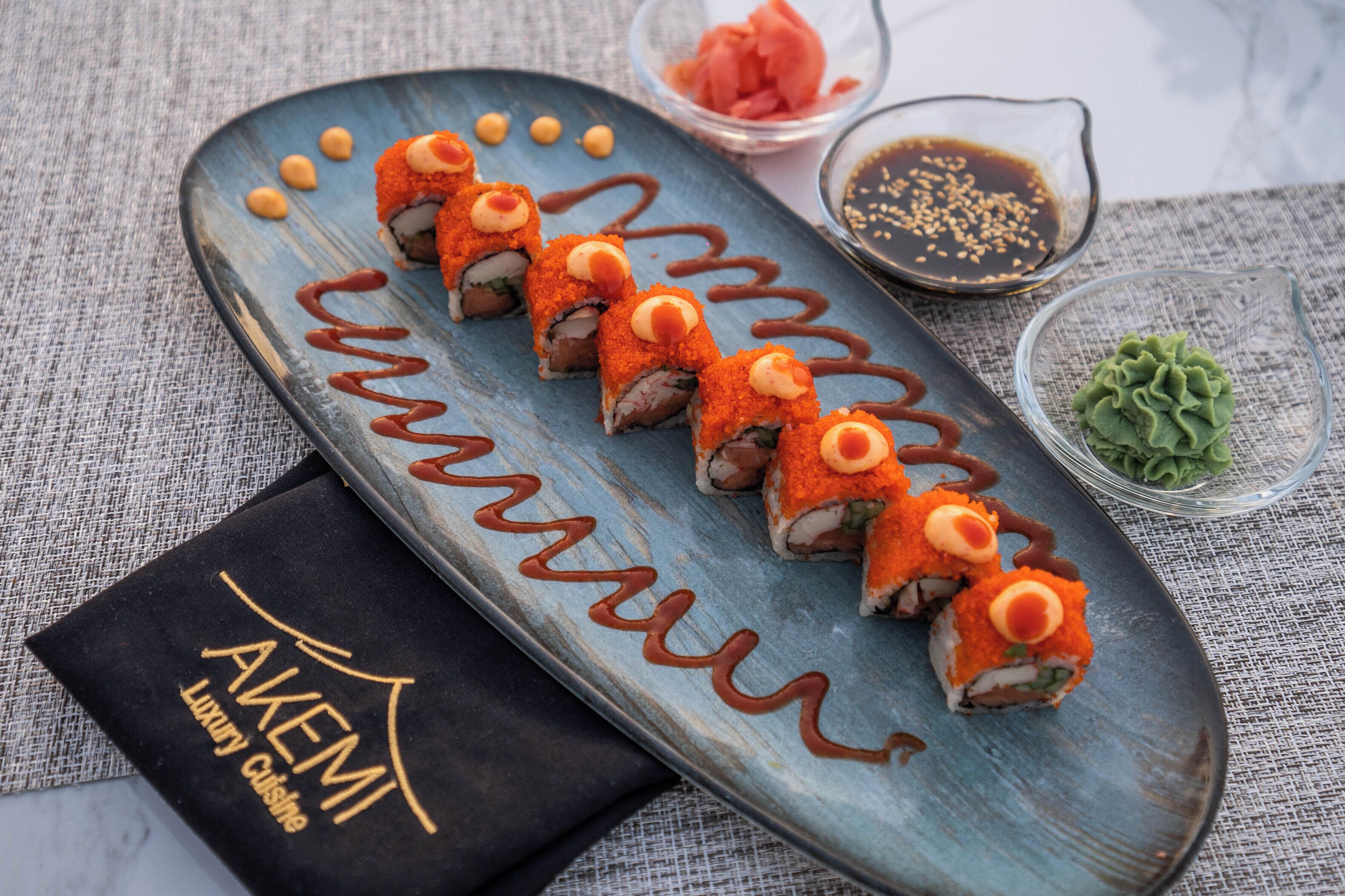 A sushi platter with nigiri and a black napkin with "AKEMI Luxury Cuisine" text.