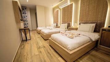Habitación de hotel con tres camas, suelo de madera y una pared con jeroglíficos.