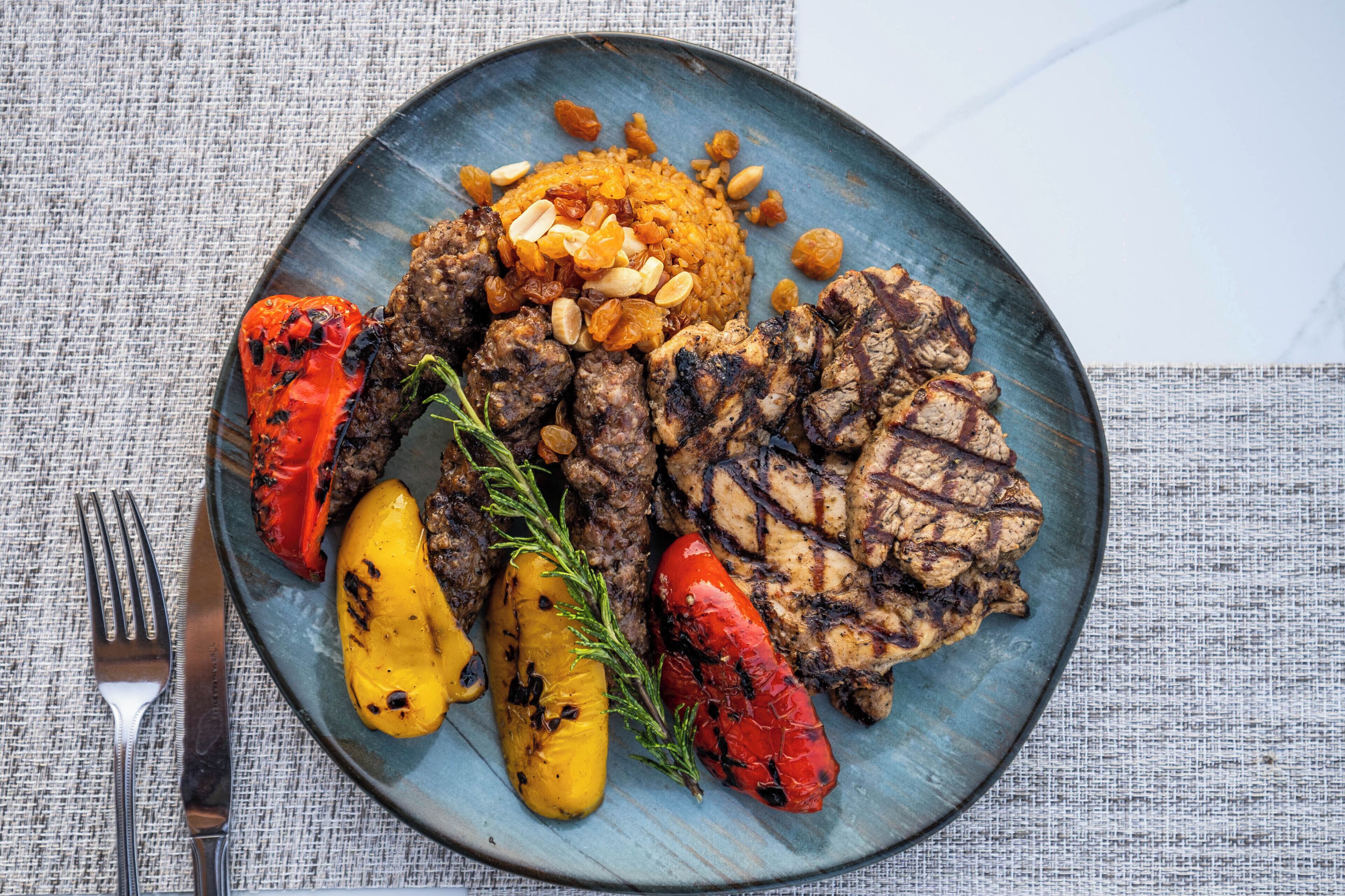 A plate with grilled meat, roasted vegetables, and a side of rice.