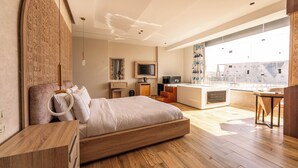 A modern bedroom with a large bed, a wooden headboard, a TV, and a balcony with a view. - Royal Great Pyramid INN (Giza)