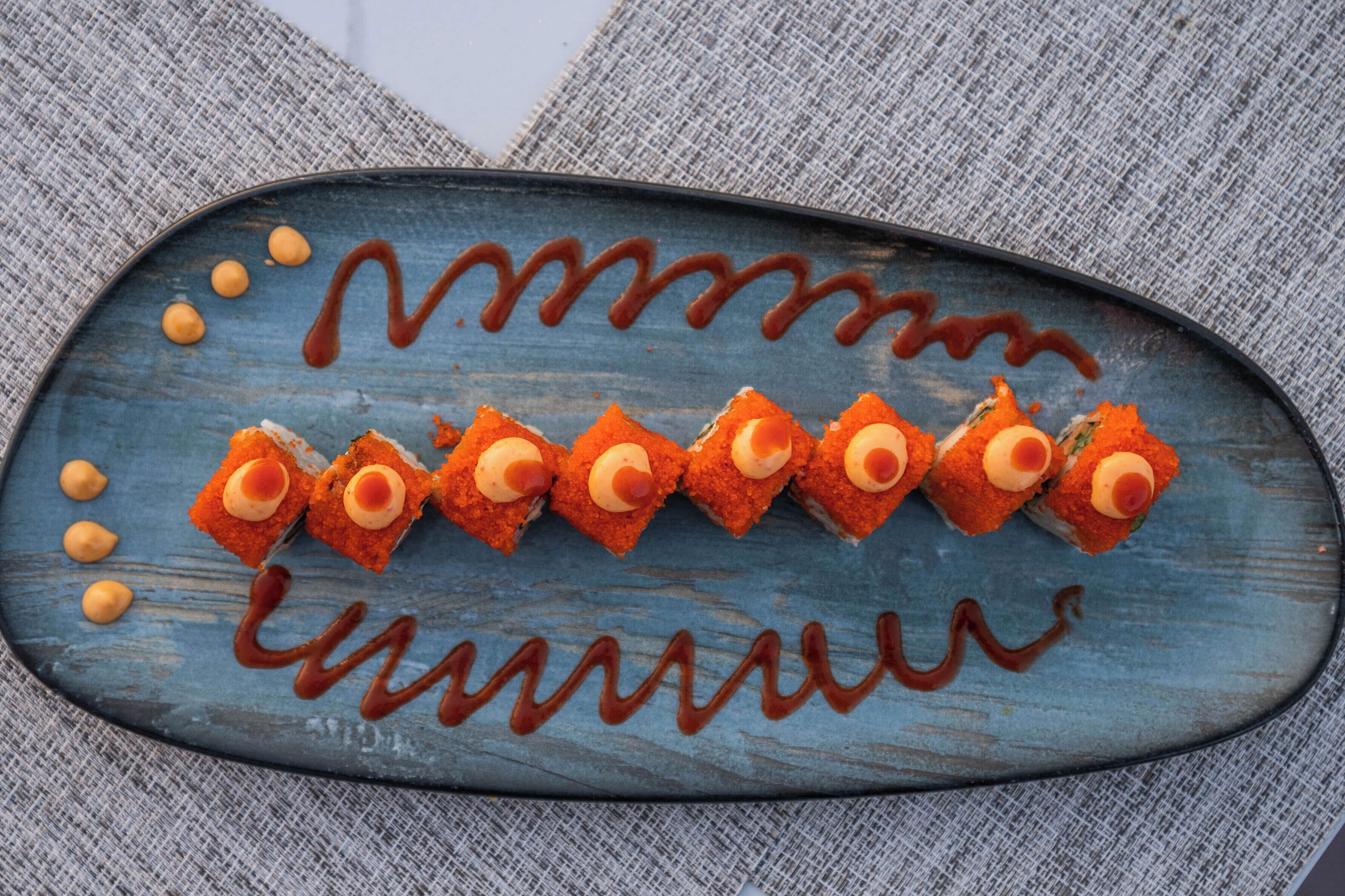 A blue oval plate with sushi pieces and sauce.