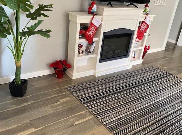 A living room with a fireplace, a potted plant, and a red poinsettia.