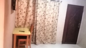 A small, dimly lit room with a single wooden chair, a small table, and a dark-colored sofa. - Vacation Inn Hotel (Accra)
