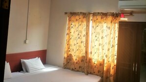 A bedroom with a single bed, a wardrobe, and an air conditioning unit. - Vacation Inn Hotel (Accra)