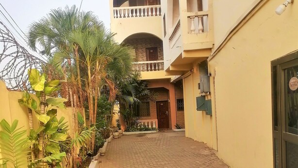 A paved pathway leading to a building with multiple balconies and a gated entrance. - Vacation Inn Hotel (Accra)