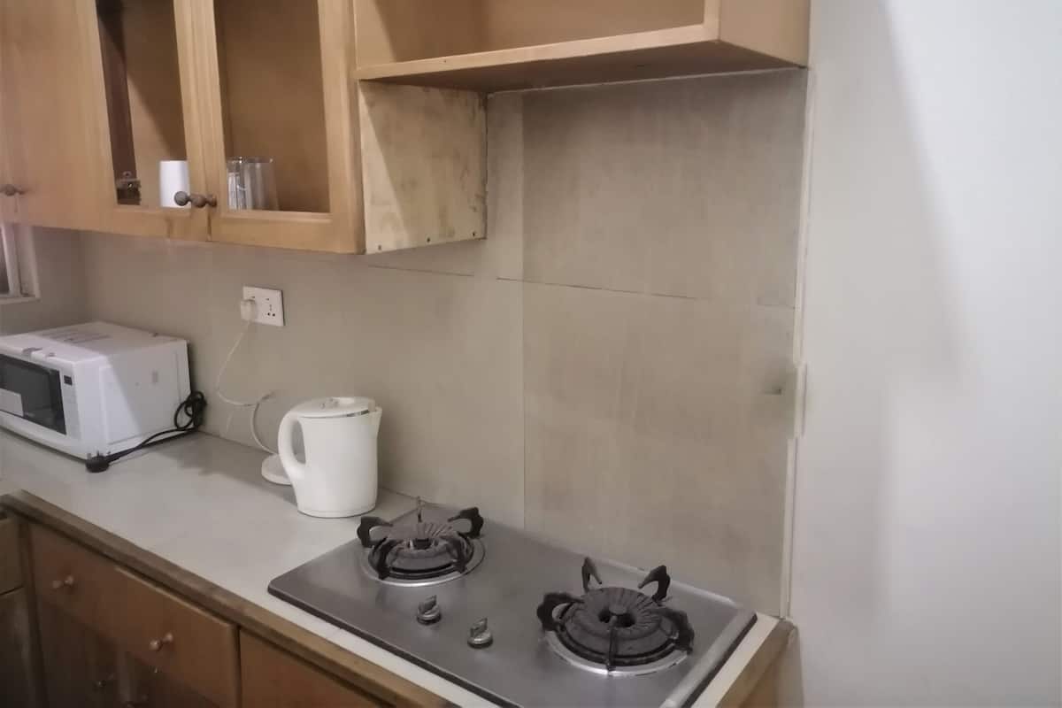 A kitchen with a microwave, kettle, and gas stove.