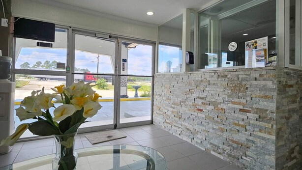 A reception area with a glass table, a vase with flowers, and a stone wall.