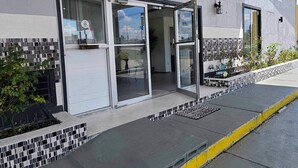 A hotel entrance with a glass door, a tiled exterior wall, and a signboard.