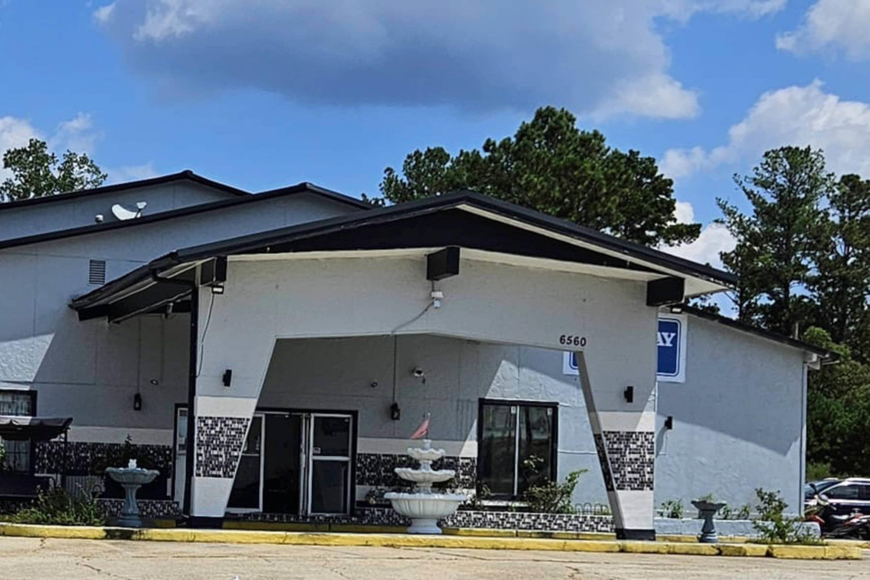 A building with a flat roof, a large entrance with a covered porch, and a parking sign.