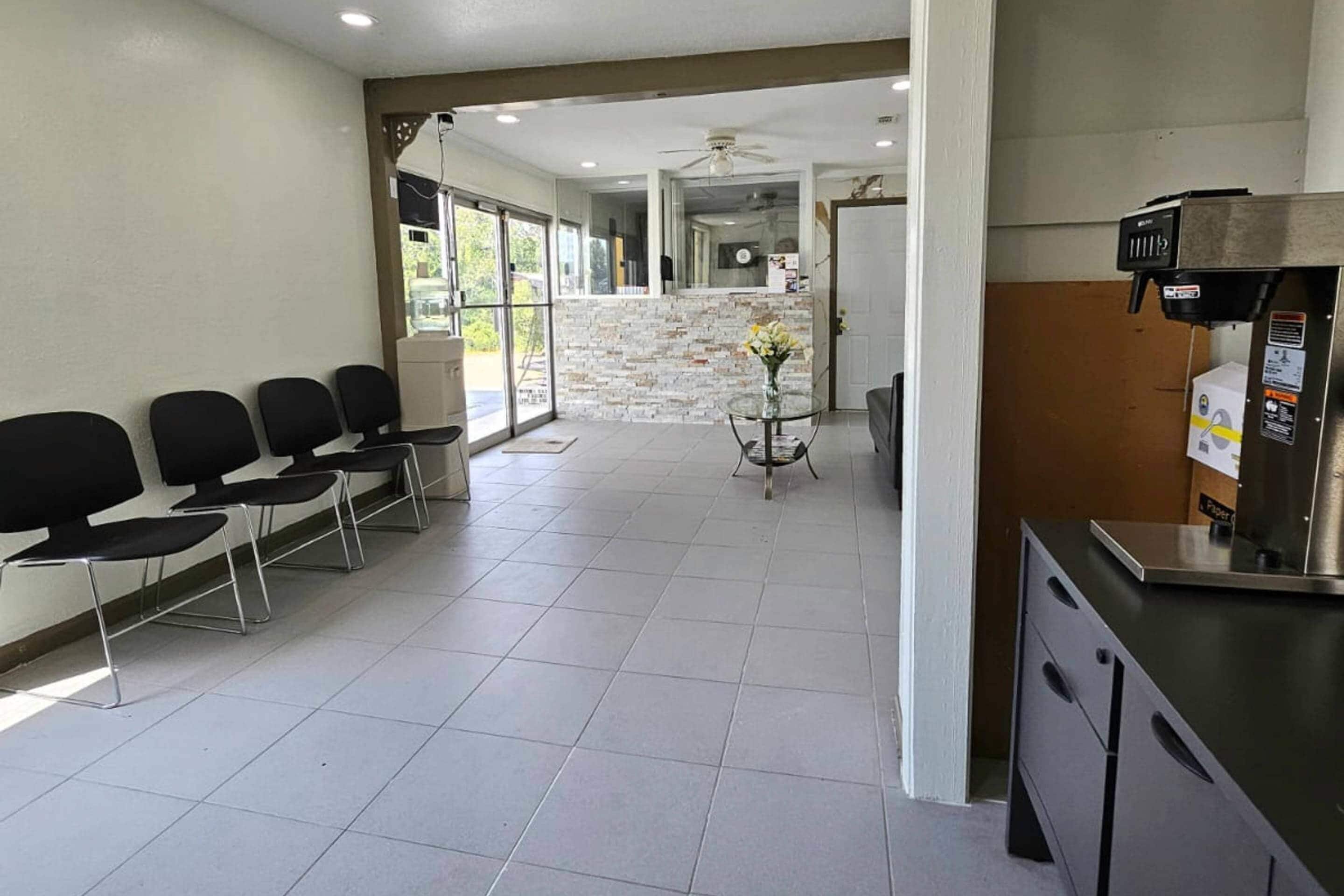 A waiting area with chairs, a reception desk, and a view of a brick wall and windows.