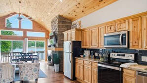 Une cuisine spacieuse avec des meubles en bois, une cheminée en pierre et une grande fenêtre donnant sur une terrasse.
