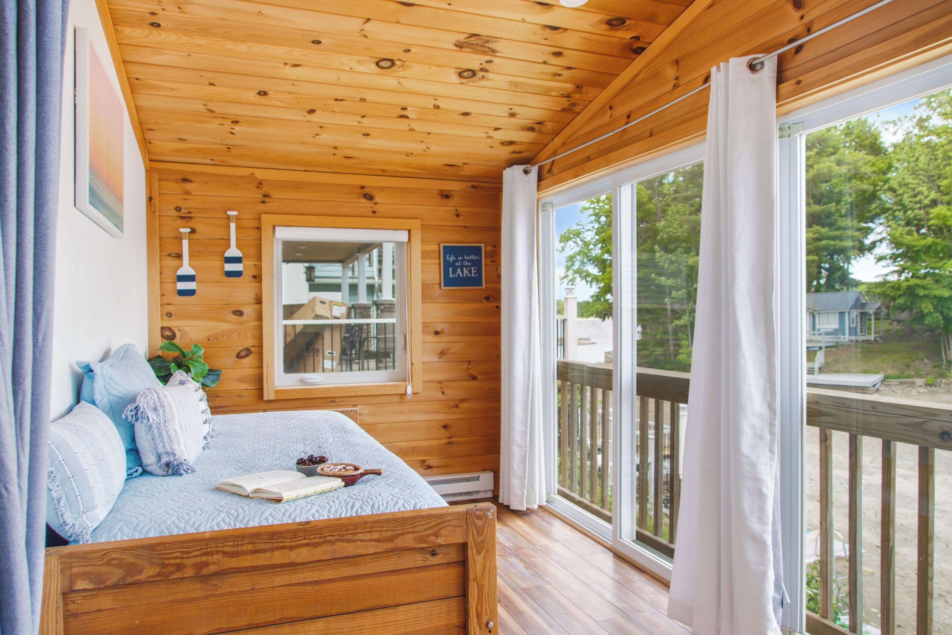Een slaapkamer in een houten chalet met een bed, kussens, een raam en een bord.