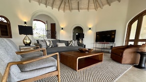 Ein geräumiges Wohnzimmer mit grauem Sofa, Holztisch und einem gemusterten Teppich.